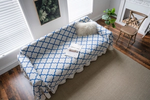 Detailed texture of thick knit sofa cover with blue clover pattern and wavy edges