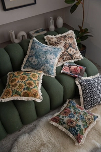 Detailed view of jacquard throw pillows featuring retro floral patterns and fringe trim