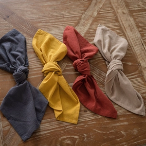Set of four washed cotton napkins in blue, yellow, red and beige on wooden table