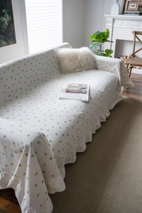 Detail of cream sofa throw with yellow lemon print and delicate ruffled edges