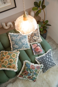 Close-up of jacquard cushion covers with fringe tassels on a dark green sofa