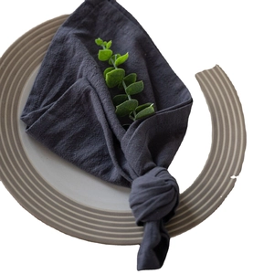Charcoal grey washed cotton napkin tied with a knot and decorative green branch