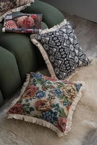 Detail of geometric and floral jacquard throw pillows with tassels on a sofa