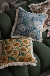 Detailed view of jacquard floral pillows with fringe on a green velvet sofa