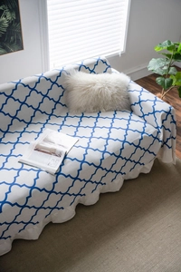 Detailed view of white sofa cover with blue geometric pattern and ruffled edges