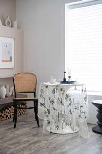 Close-up of white mesh tablecloth featuring elegant black butterfly and floral embroidery