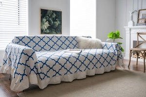 Detail of blue clover pattern on beige sofa cover with elegant ruffled edges and linen texture