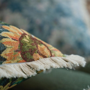 Macro detail of vintage floral jacquard pillow cover with decorative cotton fringe trim