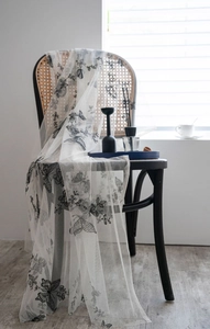 Close-up of white lace fabric with detailed black butterfly embroidery on a black chair