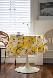 Close-up of lemon print pattern on beige tablecloth with white lace embroidery edge