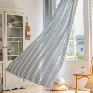 Light blue striped curtains with white tassels in a minimalist countryside home decor