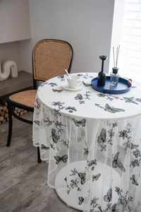 Detailed view of translucent lace tablecloth featuring black butterfly and floral embroidery
