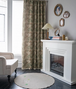 Detail of dark green floral curtain with fringed edges in a vintage style living room