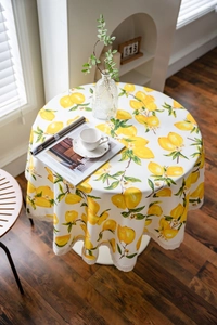 Detail of round tablecloth with fresh lemon print and delicate beige lace edging