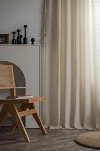 Detail of cream waffle texture curtain with delicate fringe tassels in a wabi-sabi room