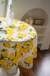 Detailed view of round lemon print tablecloth with elegant white lace border trim