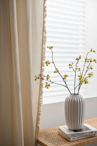 Detailed close-up of cream waffle curtain with delicate tassels and natural texture