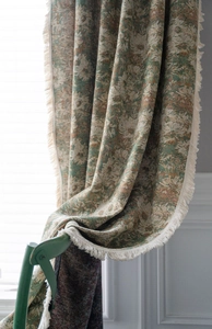 Detailed texture of green floral cotton linen curtain with cream fringe on a wooden chair