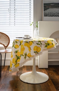 Detailed view of round white tablecloth with lemon prints and white crochet lace edges