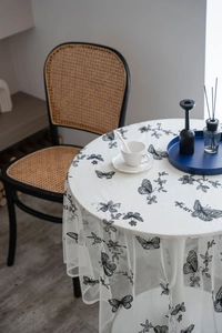 Close-up of white lace tablecloth featuring intricate black butterfly embroidery patterns