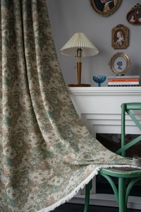 Detailed close-up of green floral pattern fabric with white fringe tassel edges