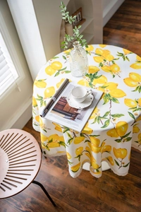 Detailed view of round tablecloth with fresh lemon prints and white lace edge finish
