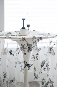 Close-up of elegant black butterfly embroidery on white tulle tablecloth with lace detail