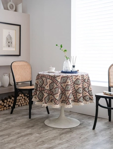 Detail of bohemian round tablecloth featuring geometric patterns and white fringe tassels