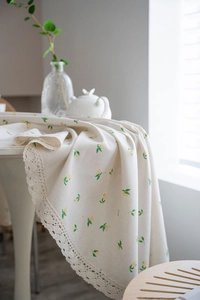 Detail of round beige tablecloth with yellow lemon floral print and lace edge crochet