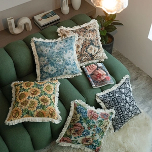 Set of five vintage jacquard throw pillows with fringe on dark green velvet sofa