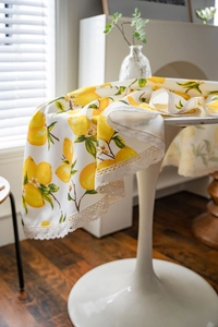 Detail of fresh lemon print tablecloth with elegant white lace border on a round table