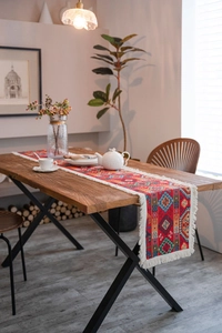 Close-up detail of red geometric jacquard table runner with decorative white tassels