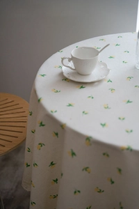 Detailed view of cream round tablecloth with lemon pattern and delicate white lace edges
