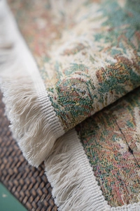 Macro detail of floral woven fabric showing green oil painting pattern and white tassels