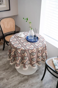 Detail of round jacquard tablecloth with bohemian geometric patterns and white tassels