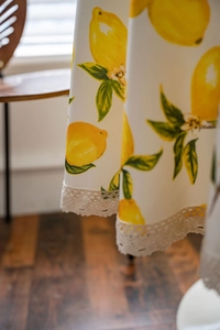 Close-up of lemon print tablecloth featuring delicate white lace edges and linen fabric