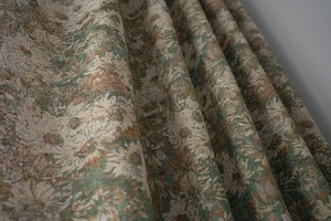 Macro detail of vintage floral jacquard fabric with dark green and beige flower patterns
