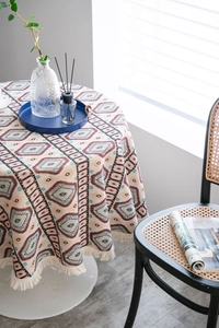 Close-up of bohemian round tablecloth featuring geometric patterns and edge tassels