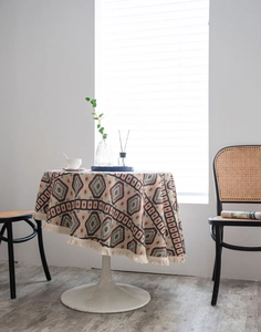 Close-up of thick geometric jacquard tablecloth with beige tassels on a round table