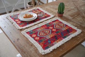 Close-up of red Bohemian woven placemats with geometric patterns and white cotton tassels