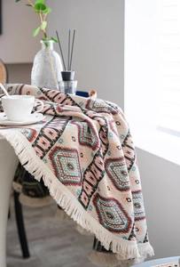 Detail of bohemian jacquard tablecloth with geometric patterns and fringe tassels
