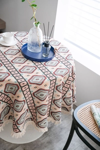 Detail of round boho tablecloth featuring geometric patterns and beige tassel fringe