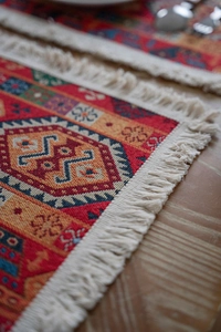 Close-up of red geometric jacquard runner featuring intricate weaving and cream tassels