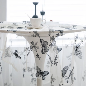 Round white lace tablecloth featuring delicate black butterfly and floral embroidery detail