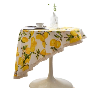 Fresh lemon print round tablecloth with white lace edges on a wooden pedestal table