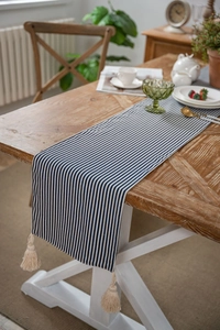 Close-up of blue and white striped table runner with elegant decorative tassels