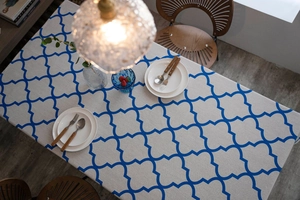 Close-up of blue clover pattern tablecloth with warm lighting and elegant table setting