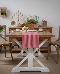 Detail of red and white striped table runner with elegant cream fringe tassels