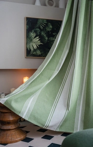 Detailed texture of green striped cotton linen fabric curtain in a rustic interior setting
