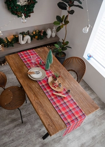 Detail of red and blue Scottish plaid table runner on wooden table with holiday decor